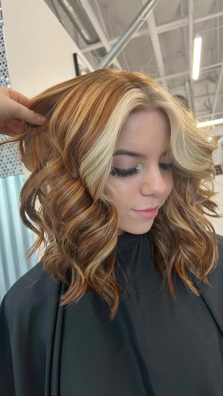 Auburn curls with bright blonde face-framing pieces in a salon.