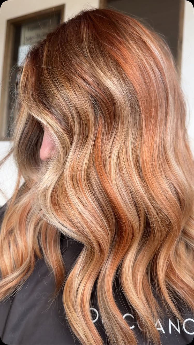 Wavy copper-red hair with blended blonde balayage highlights