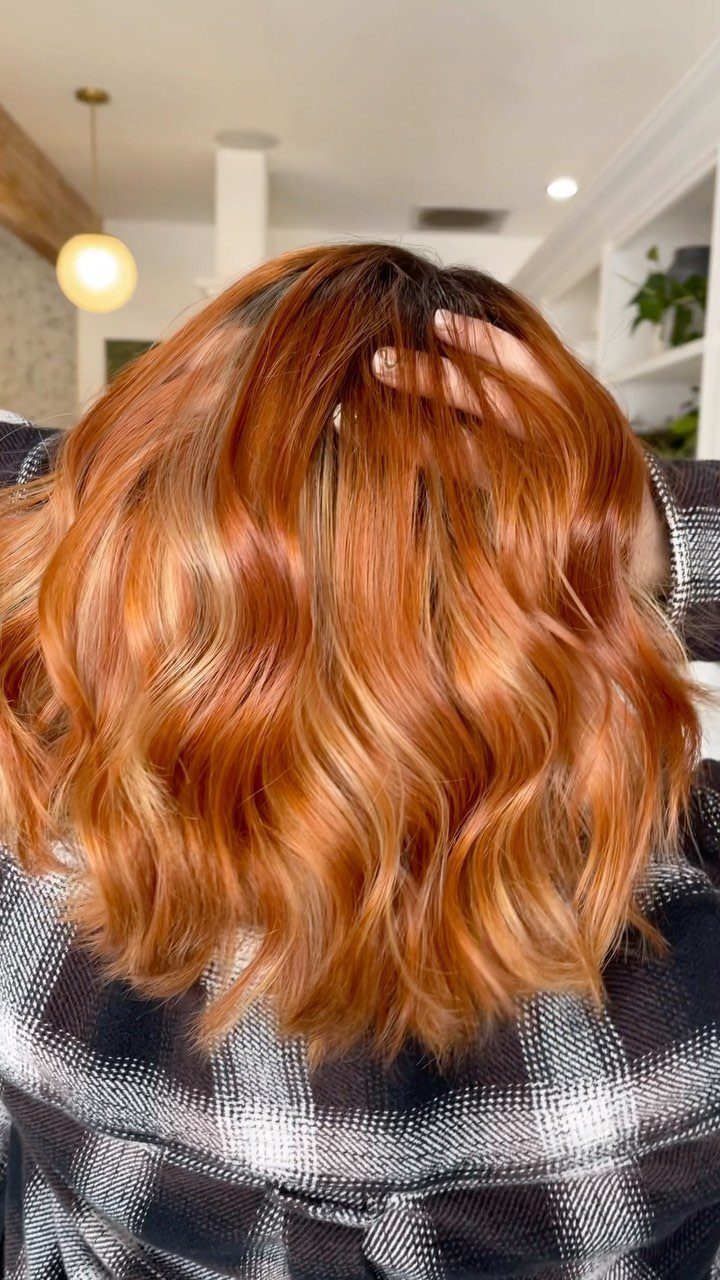 Wavy ginger-red hair with strawberry-blonde highlights in a salon