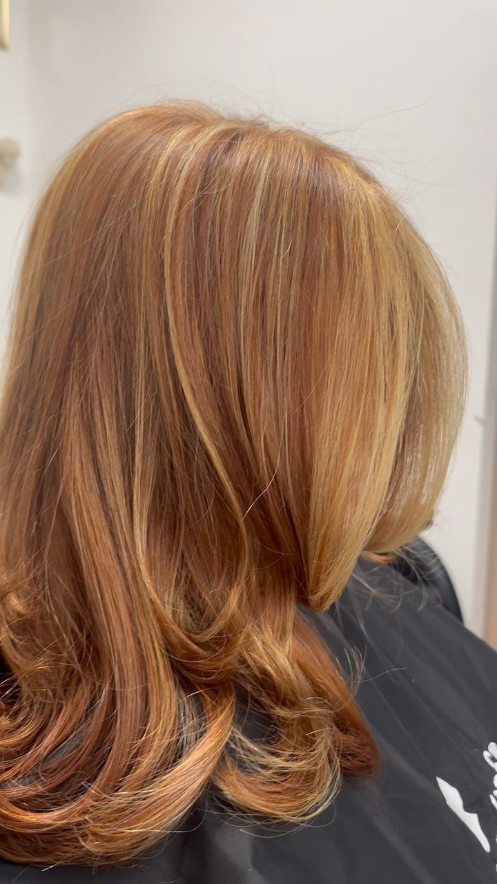 Layered ginger-red hair with subtle golden-blonde highlights and curled ends