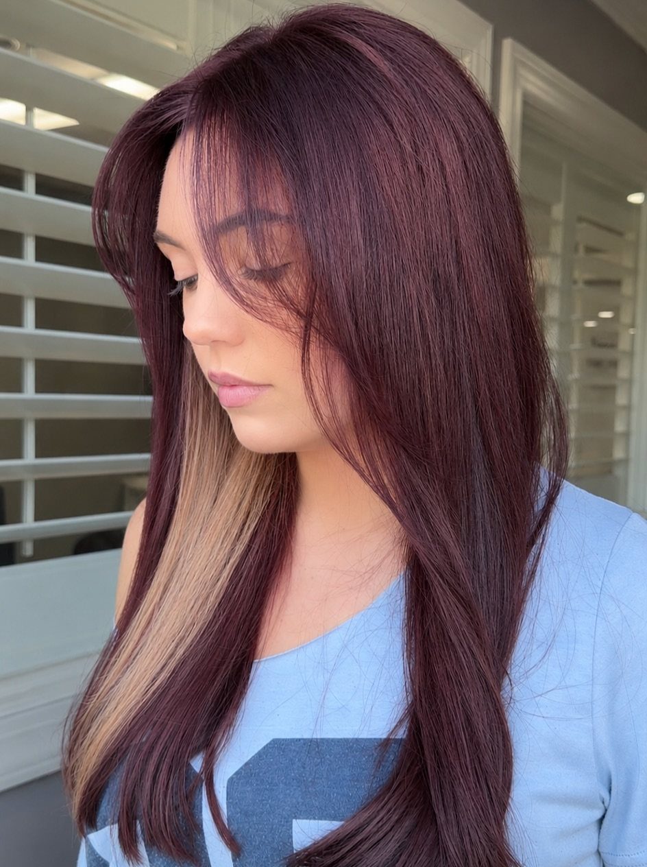 Long burgundy-red hair reveals blonde peek-a-boo highlights beneath the top layers