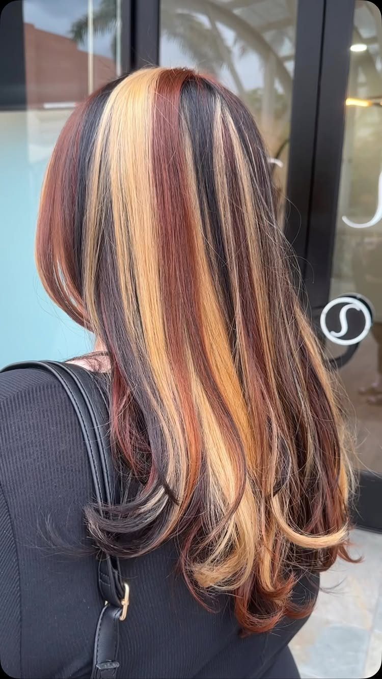Long layered brown hair with blonde highlights and copper-red streaks
