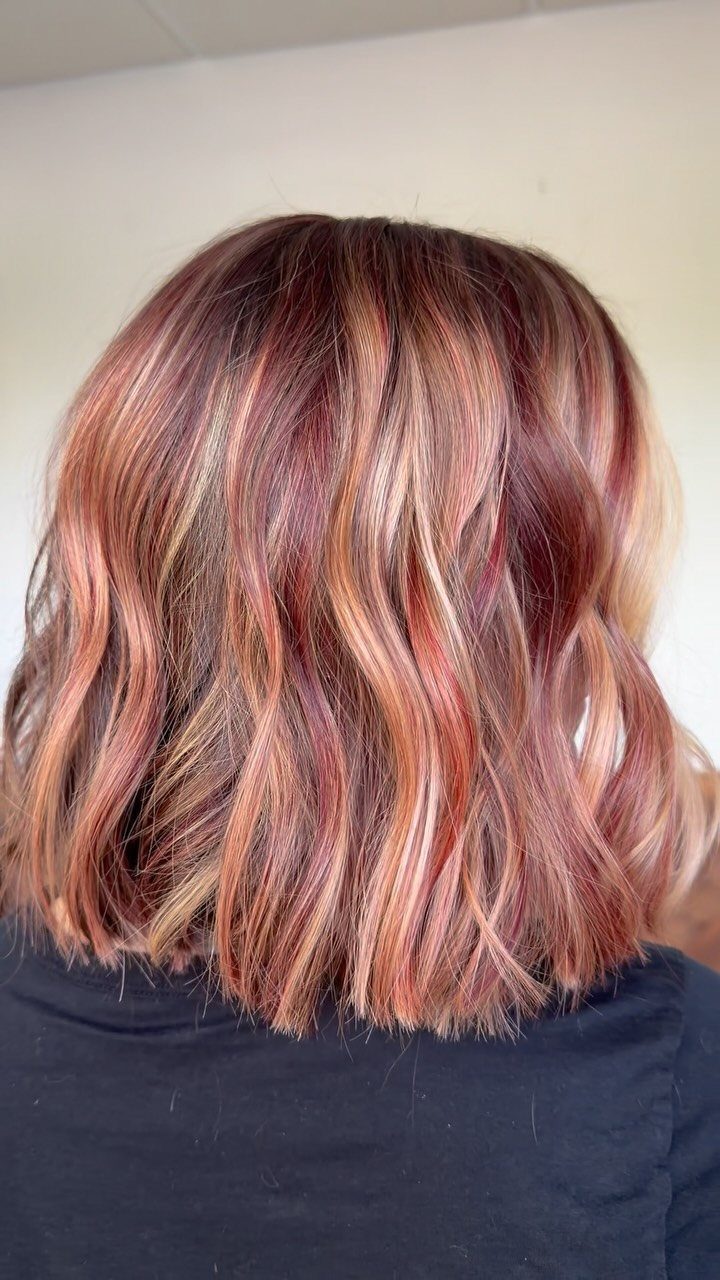 Wavy red-brown hair with pink, copper, and blonde highlights