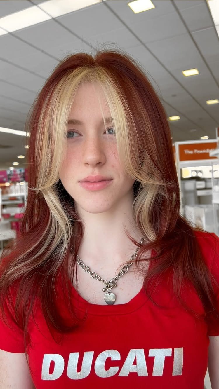 Red-haired woman with blonde face-framing highlights wearing a red Ducati shirt