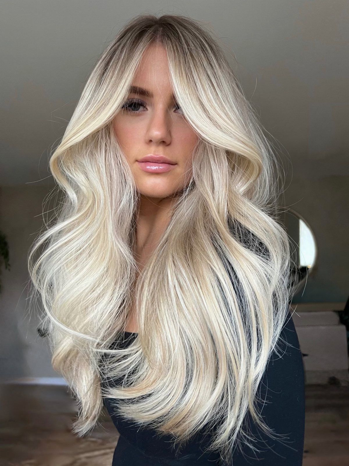 Woman with long platinum blonde hair and dark roots framing her face