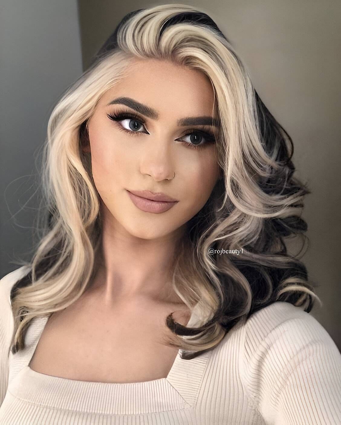 Woman with black curls and blonde highlights scattered through face-framing sections