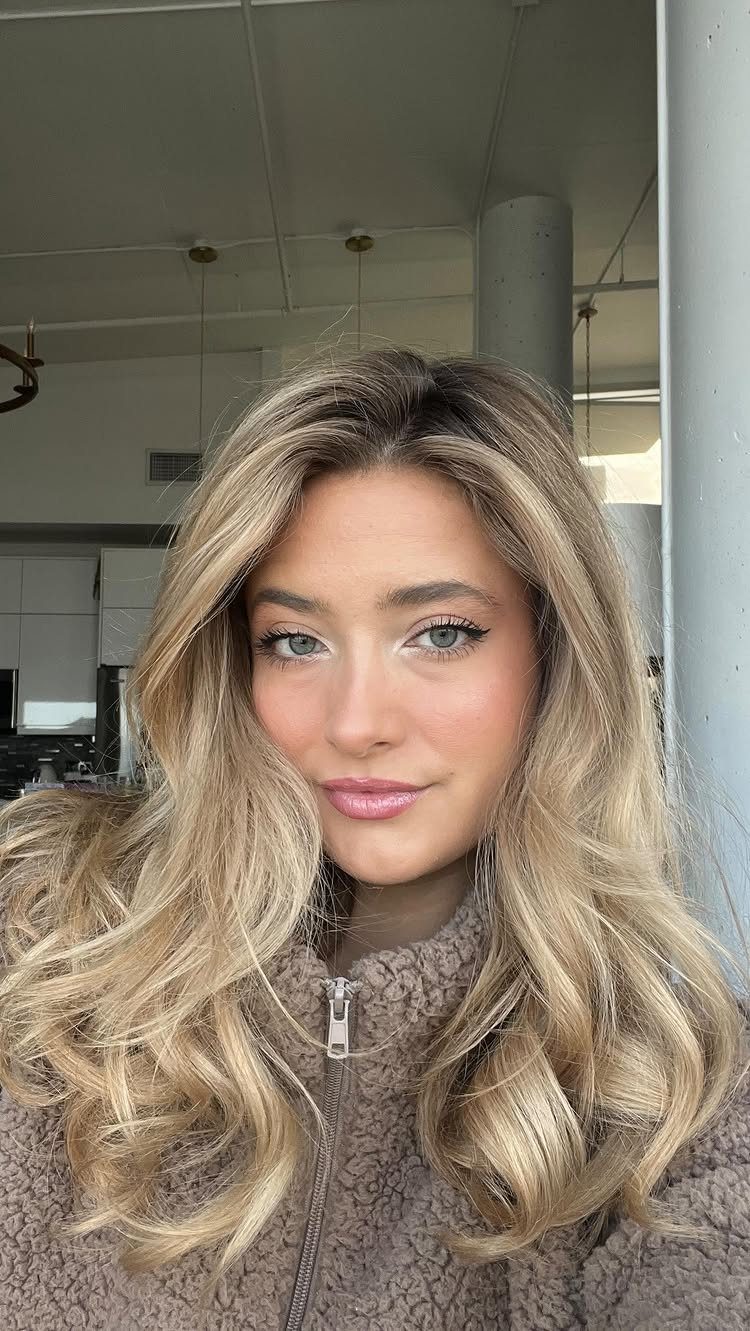 Woman with long, softly waved bronde hair and subtle darker roots