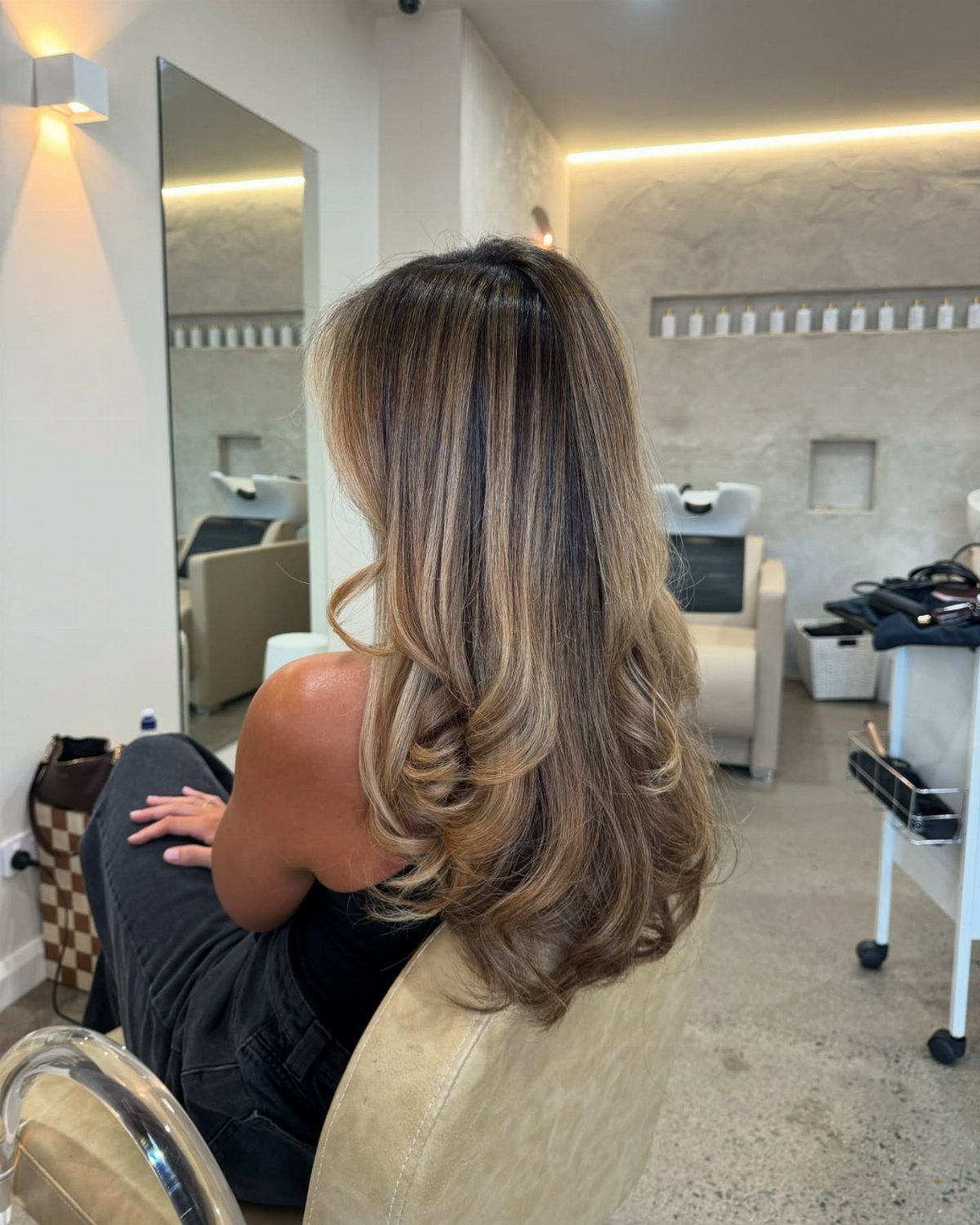 Long layered brown hair with blended blonde and caramel highlights in salon curls