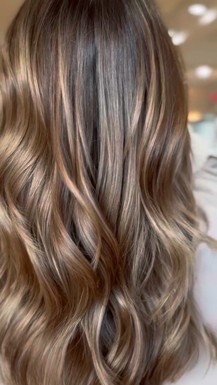 Long wavy dark brown hair with blended caramel and beige highlights