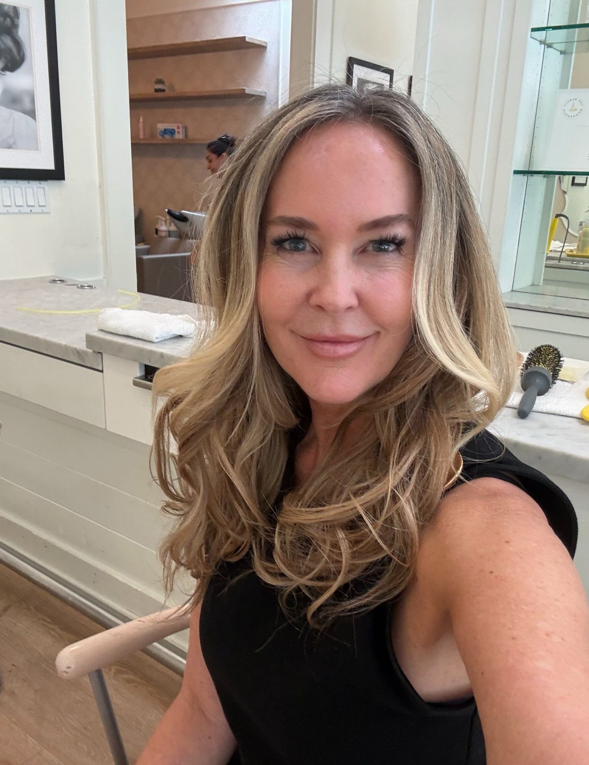 Woman with long wavy dirty blonde hair and warm caramel highlights in a salon