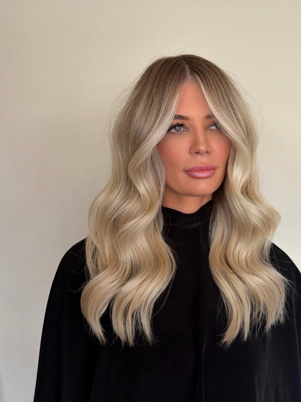 Woman with long blonde balayage waves and light face-framing highlights