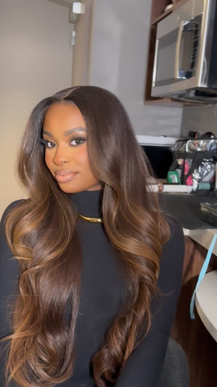 Woman with long mocha-brown curls and warm caramel highlights in a salon