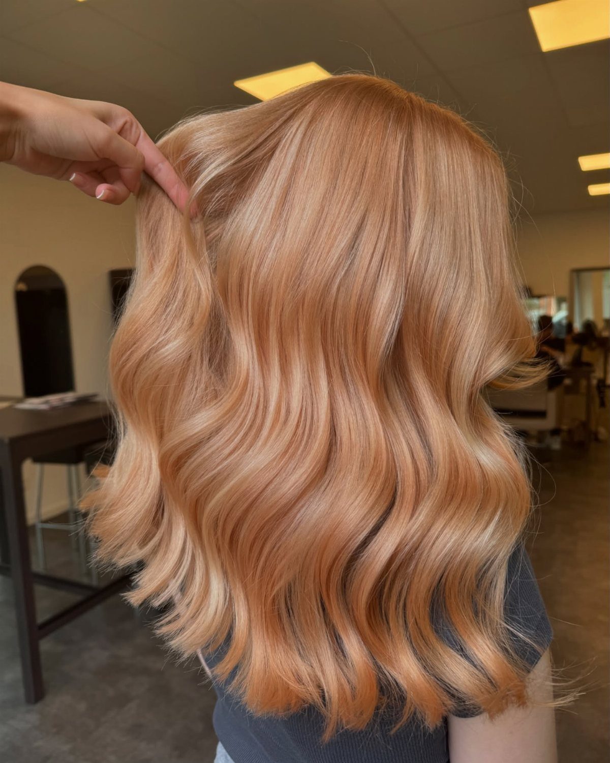 Wavy strawberry blonde hair with warm auburn and copper tones in a salon