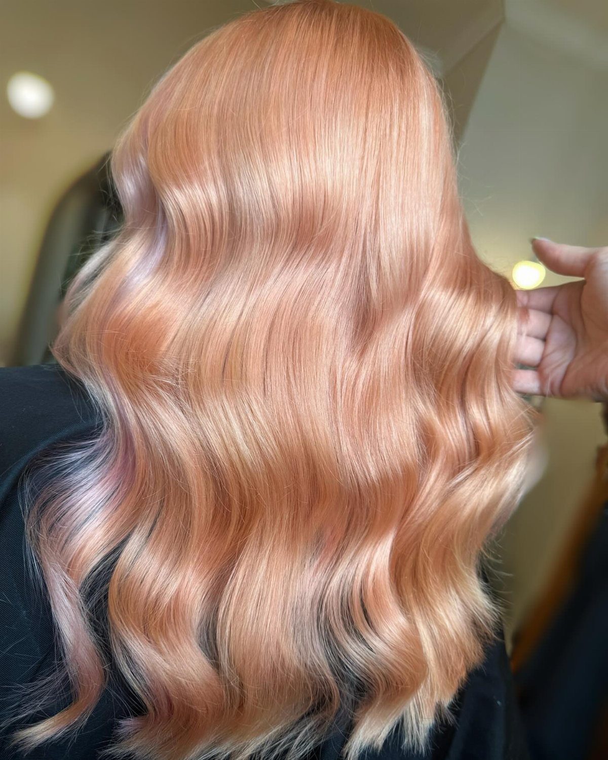 Peachy strawberry-blonde waves with lighter ends shown in a salon