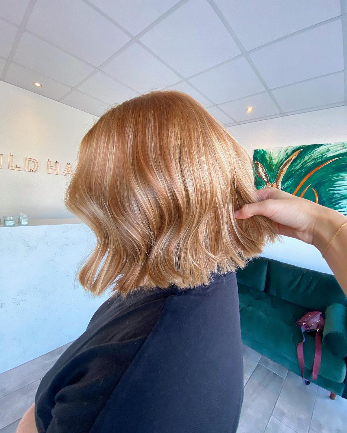 Short copper-blonde bob with softly waved ends viewed from behind in a salon