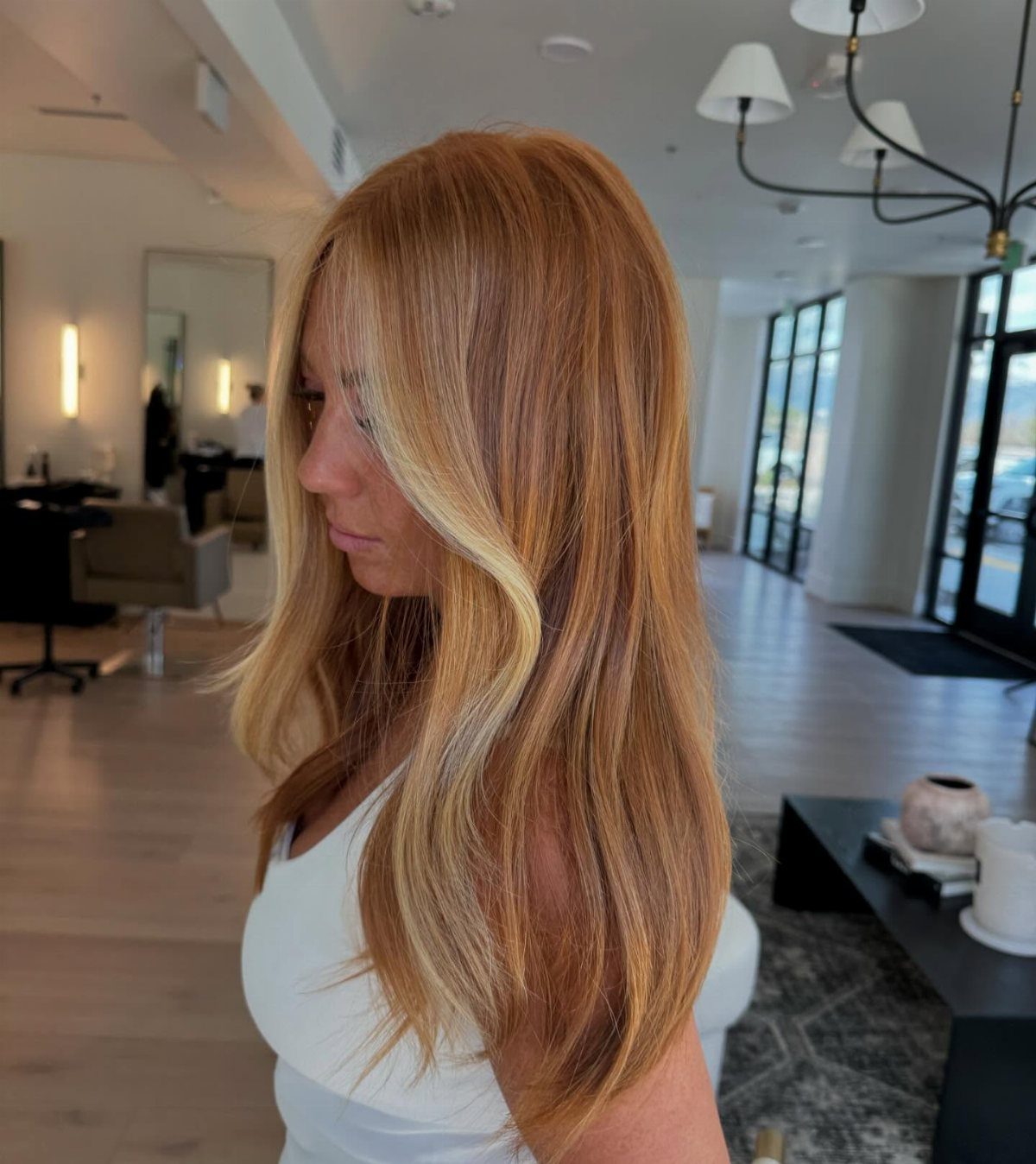 Woman showing copper strawberry blonde hair with bright blonde face-framing pieces