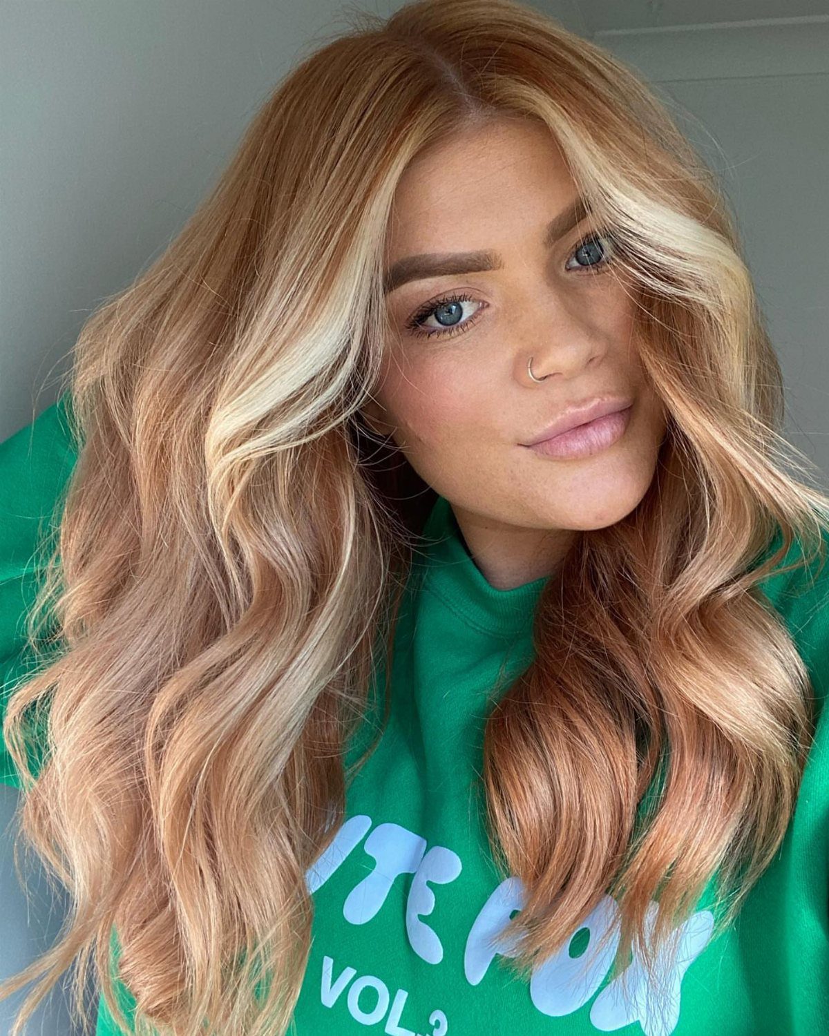 Woman with long wavy copper strawberry blonde hair and lighter highlights