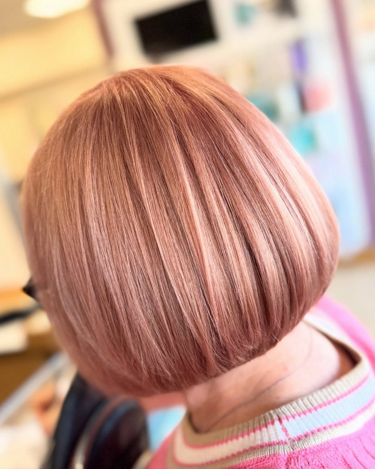 Short bob haircut showing pink strawberry-blonde hair with lighter highlights