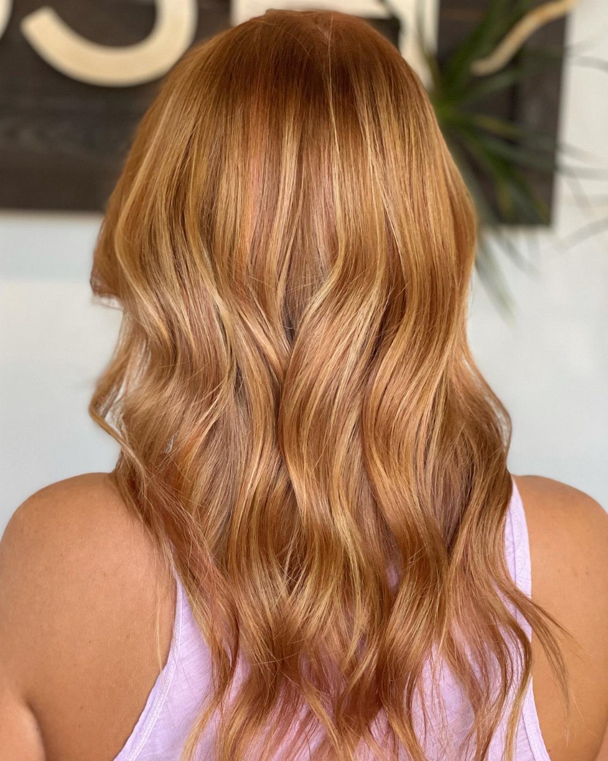 Long strawberry-blonde waves with golden copper highlights and warm orange tones