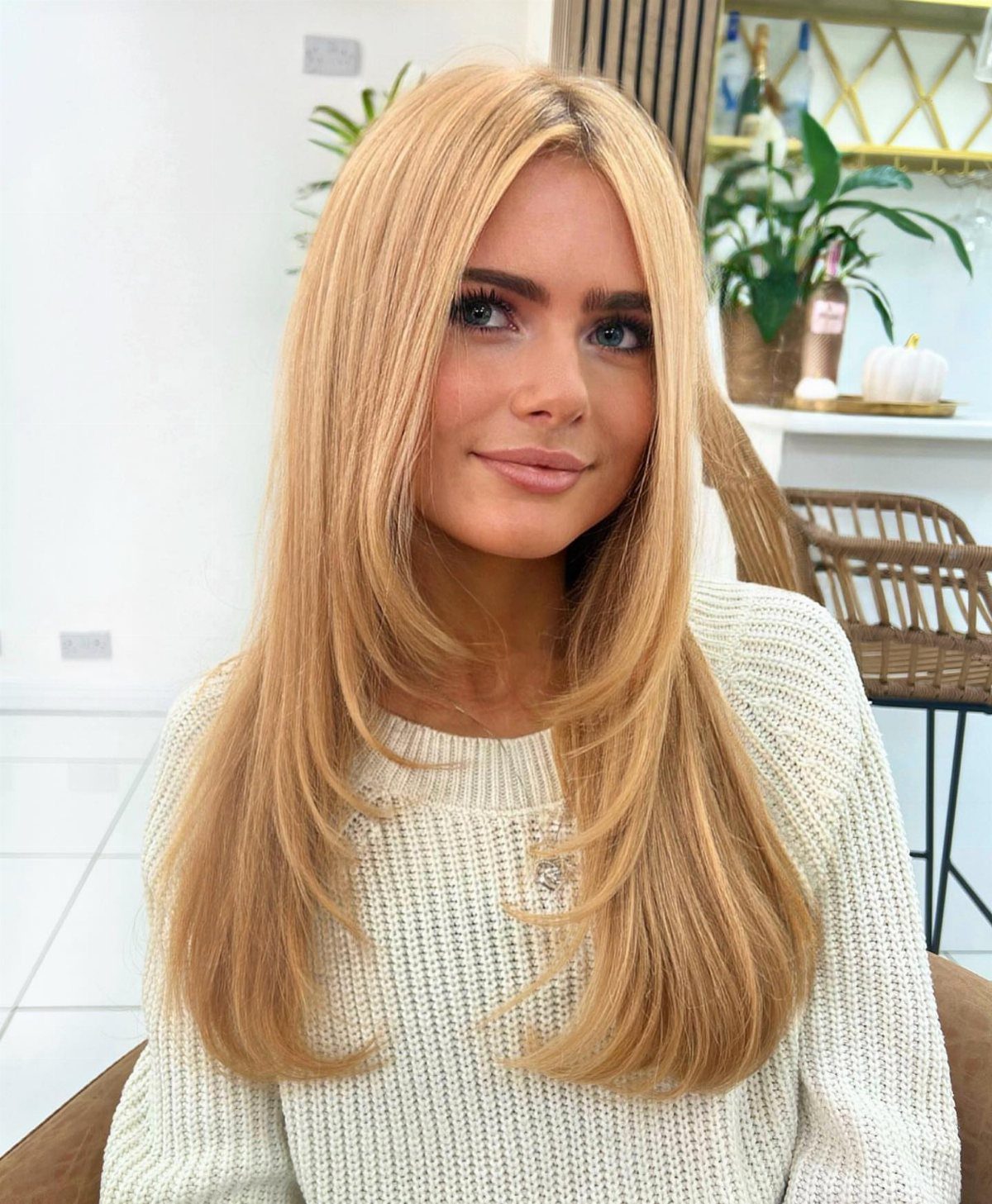 Woman with long warm blonde hair and subtle strawberry-toned highlights in a salon