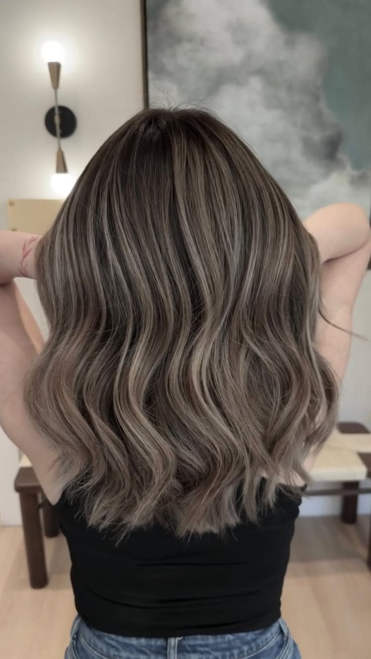 Wavy brunette hair blends into soft blonde balayage highlights