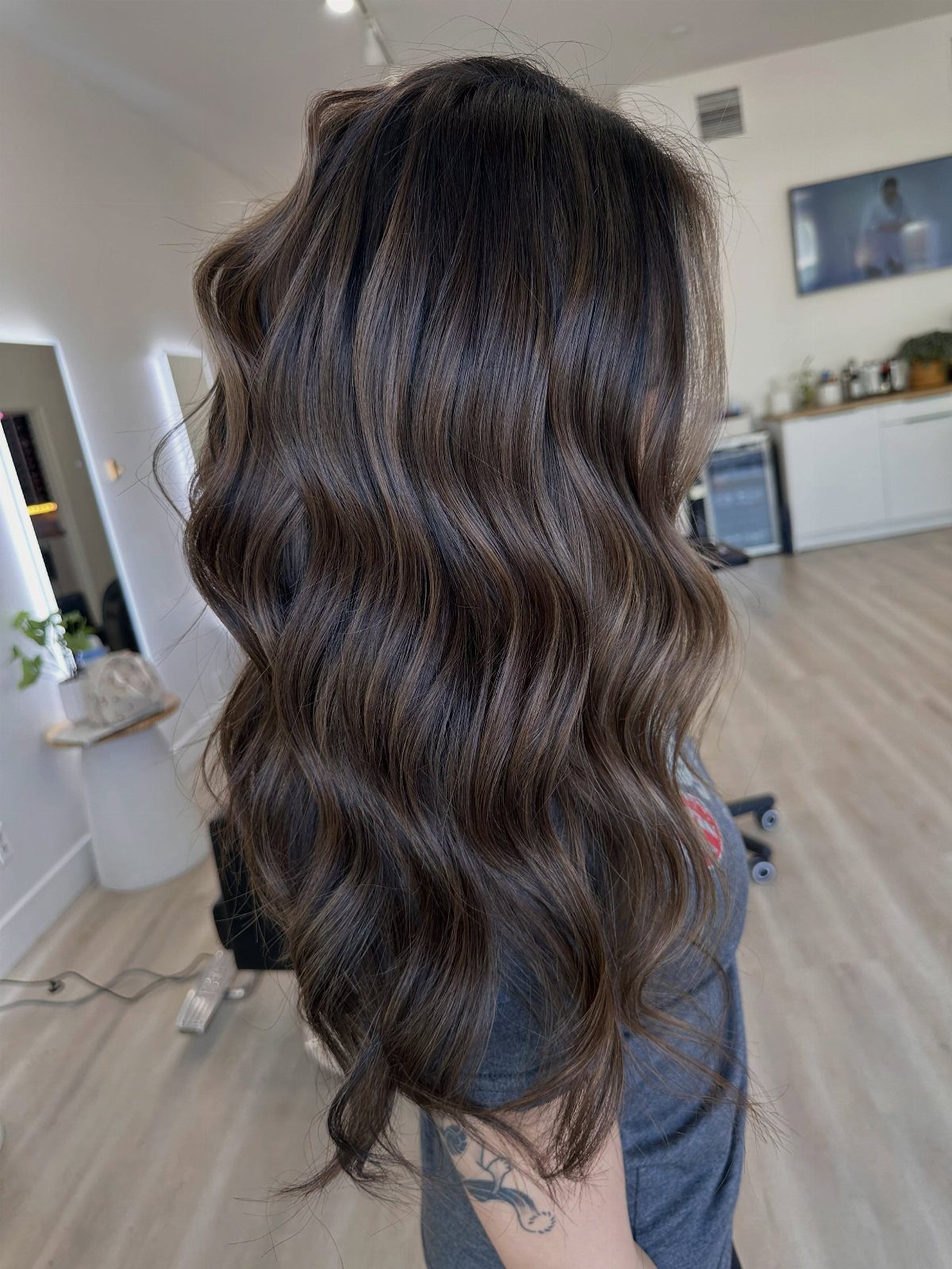 Layered dark brown hair with subtle sunlit balayage highlights and loose waves