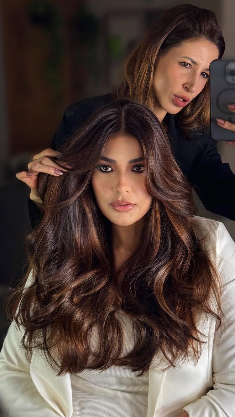 Long chocolate-brown hair with subtle brown highlights styled in loose, voluminous waves