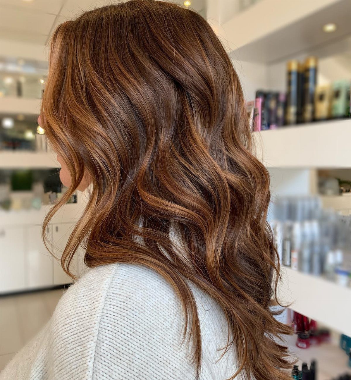 Wavy brown hair with warm cinnamon highlights in a bright salon