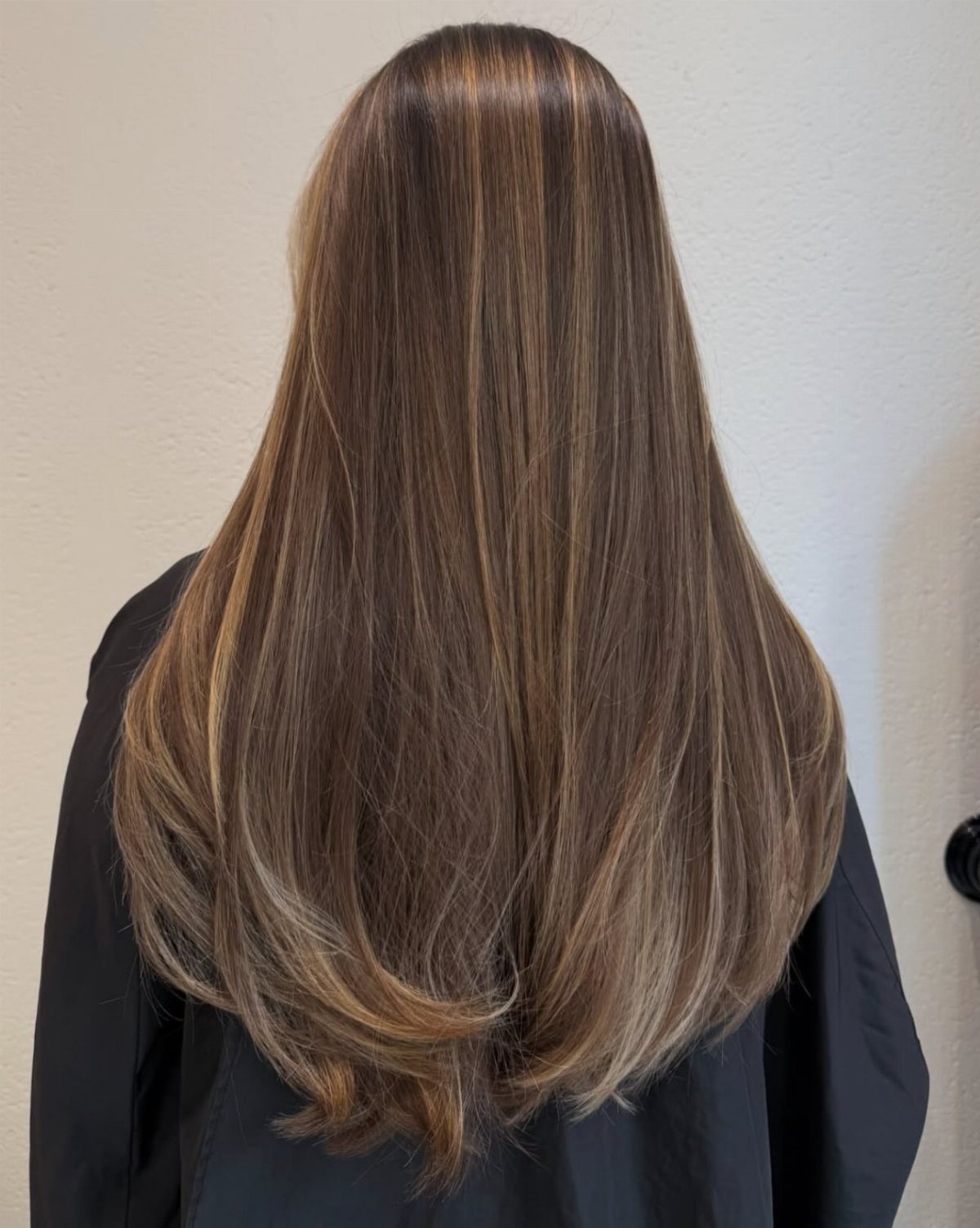 Long dark brown hair with subtle balayage highlights and softly curled ends