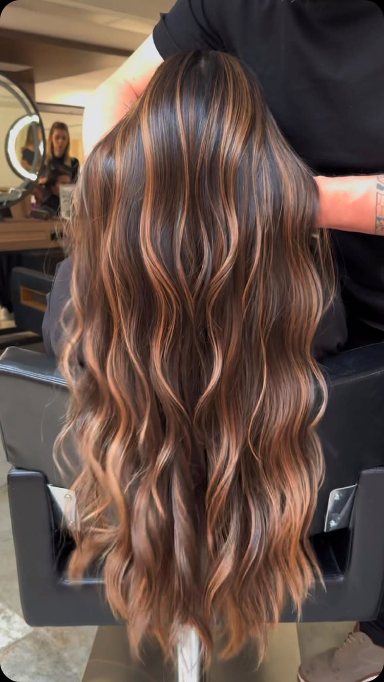 Long brown waves with bold caramel and blonde balayage in a salon