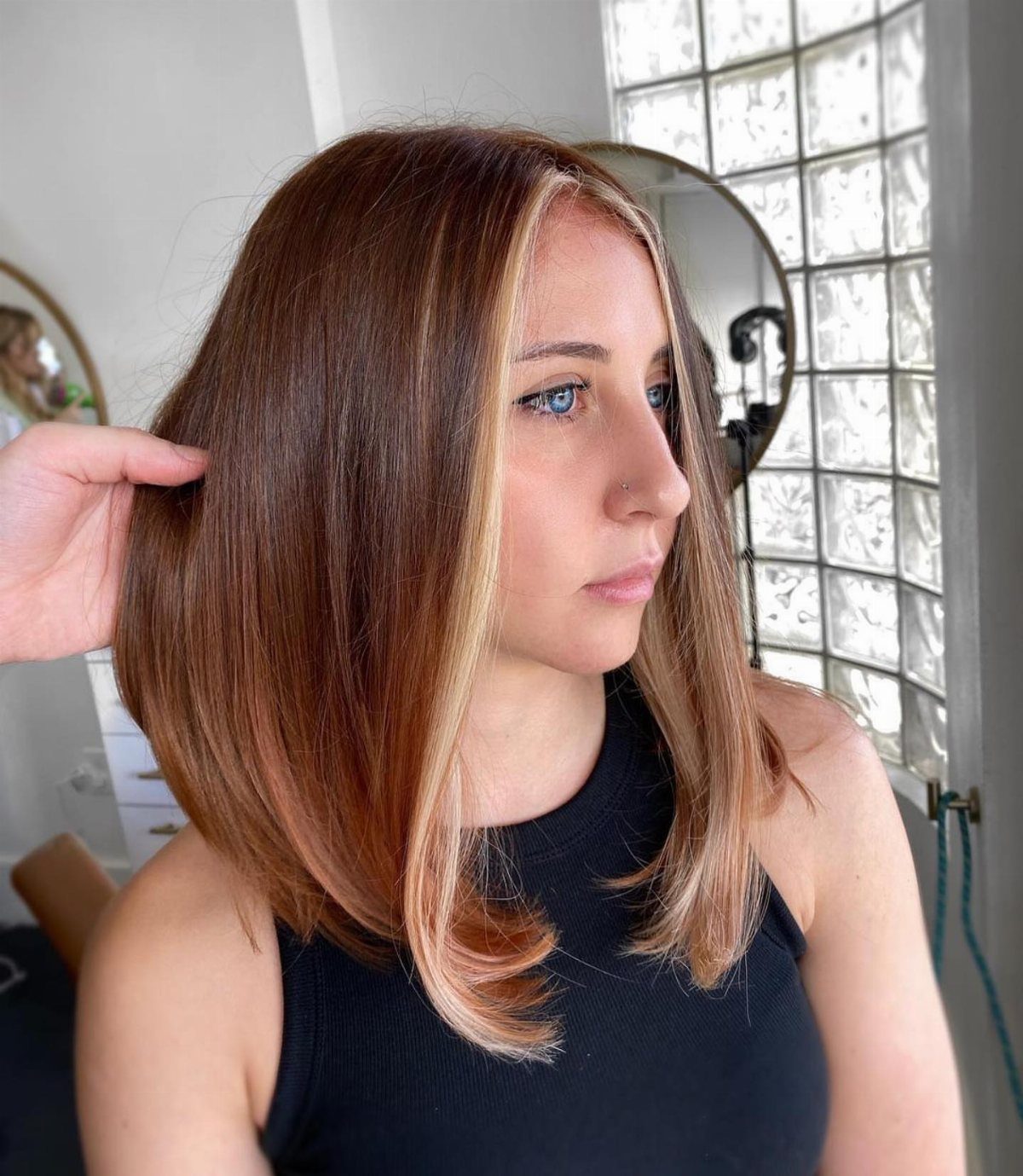 Woman with brown hair and honey-blonde face-framing balayage pieces