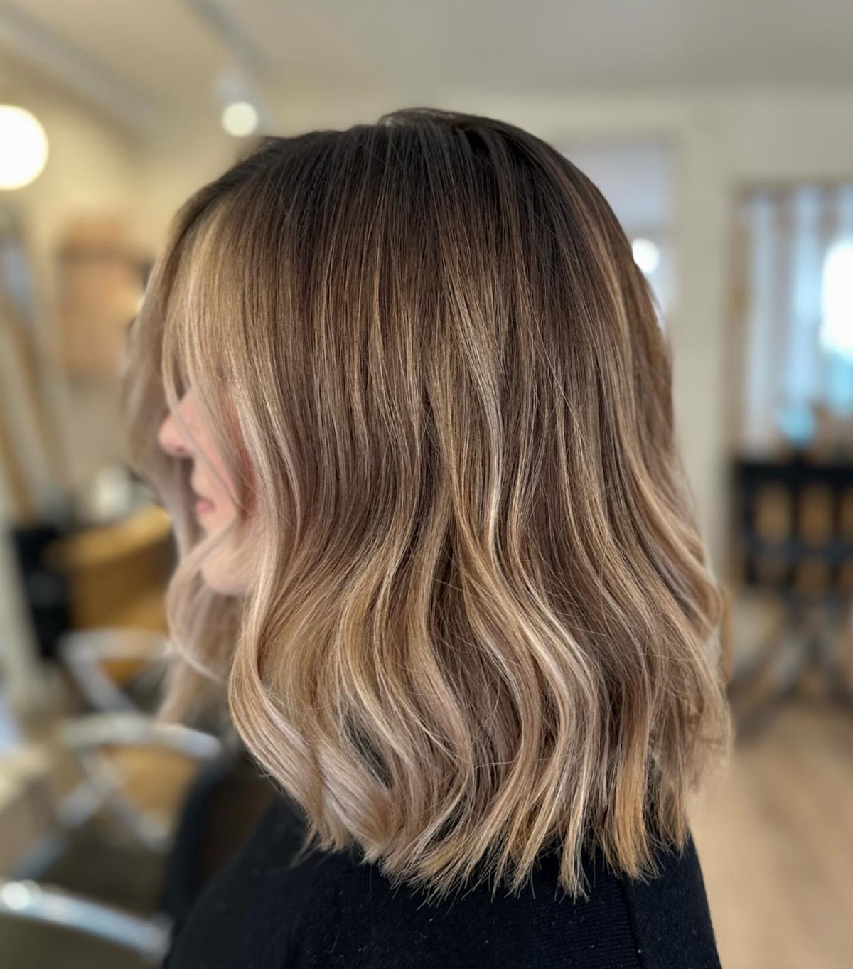 Wavy brown balayage with soft light-brown highlights in a salon