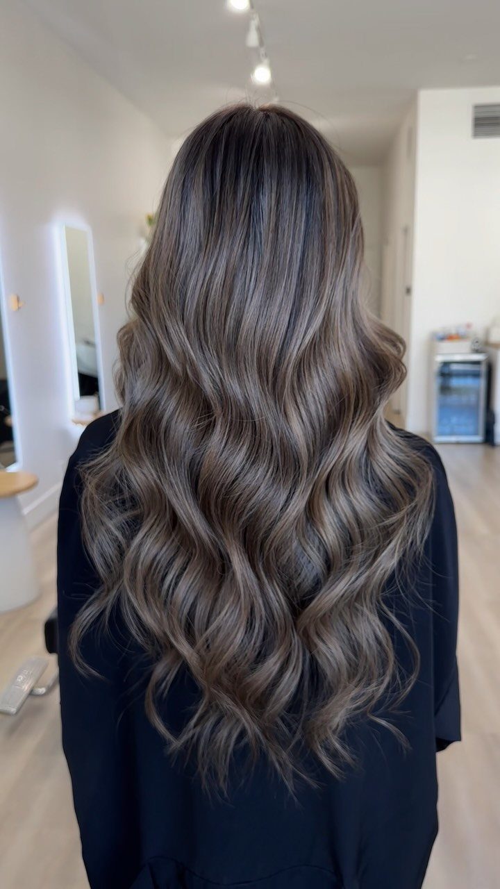 Long wavy brown hair shows layered lighter and darker balayage tones