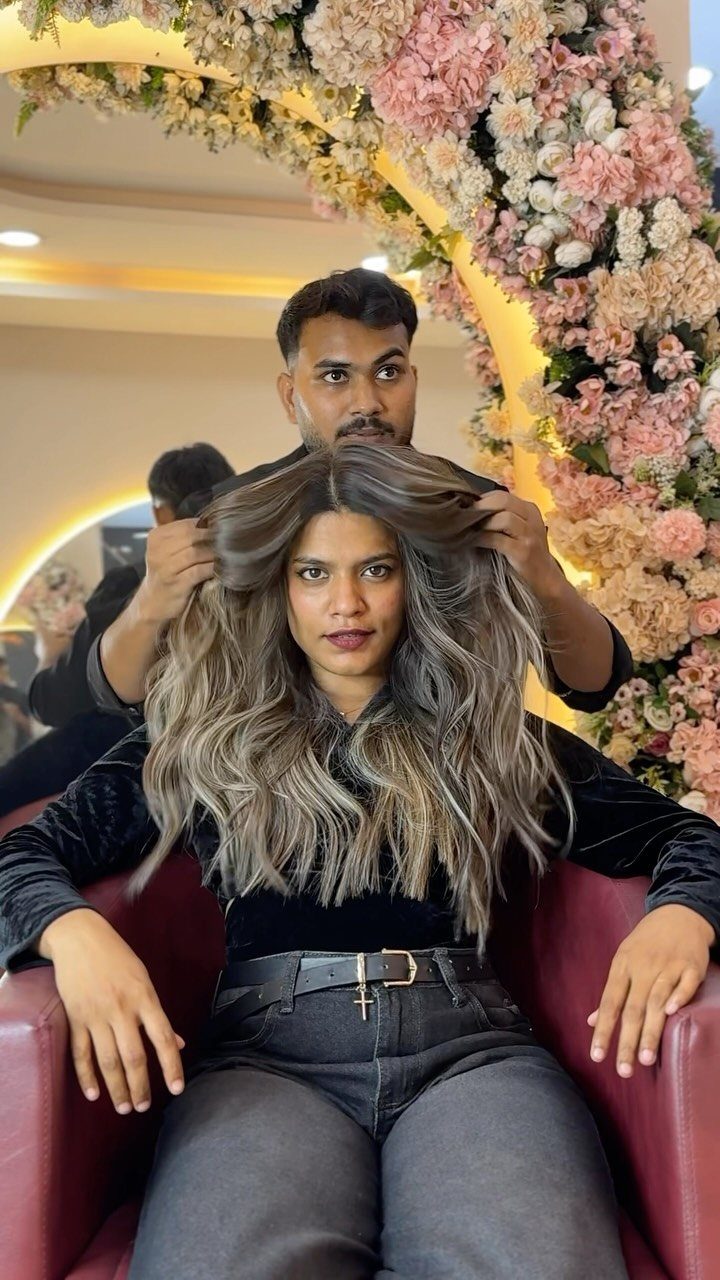 Woman with long dark brown hair and cool ash-blonde highlights seated in a salon