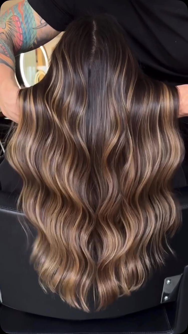 Long wavy brunette hair with softly blended caramel and beige highlights