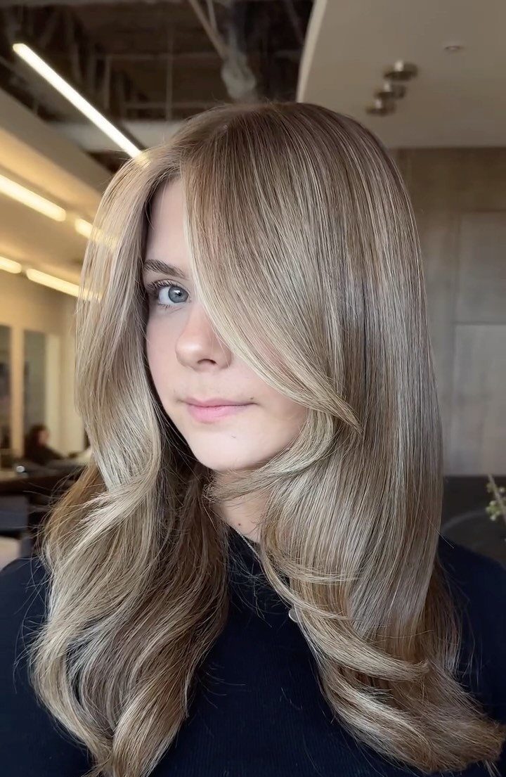 Long light brown hair with cool, muted blonde highlights and soft curls