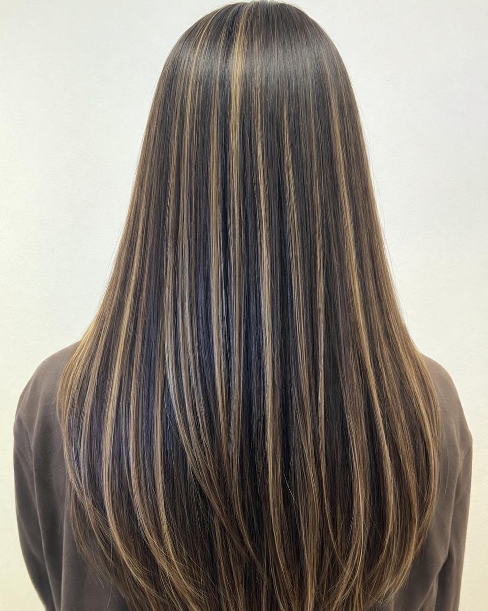 Long brown hair with fine blonde highlights falling straight down the back