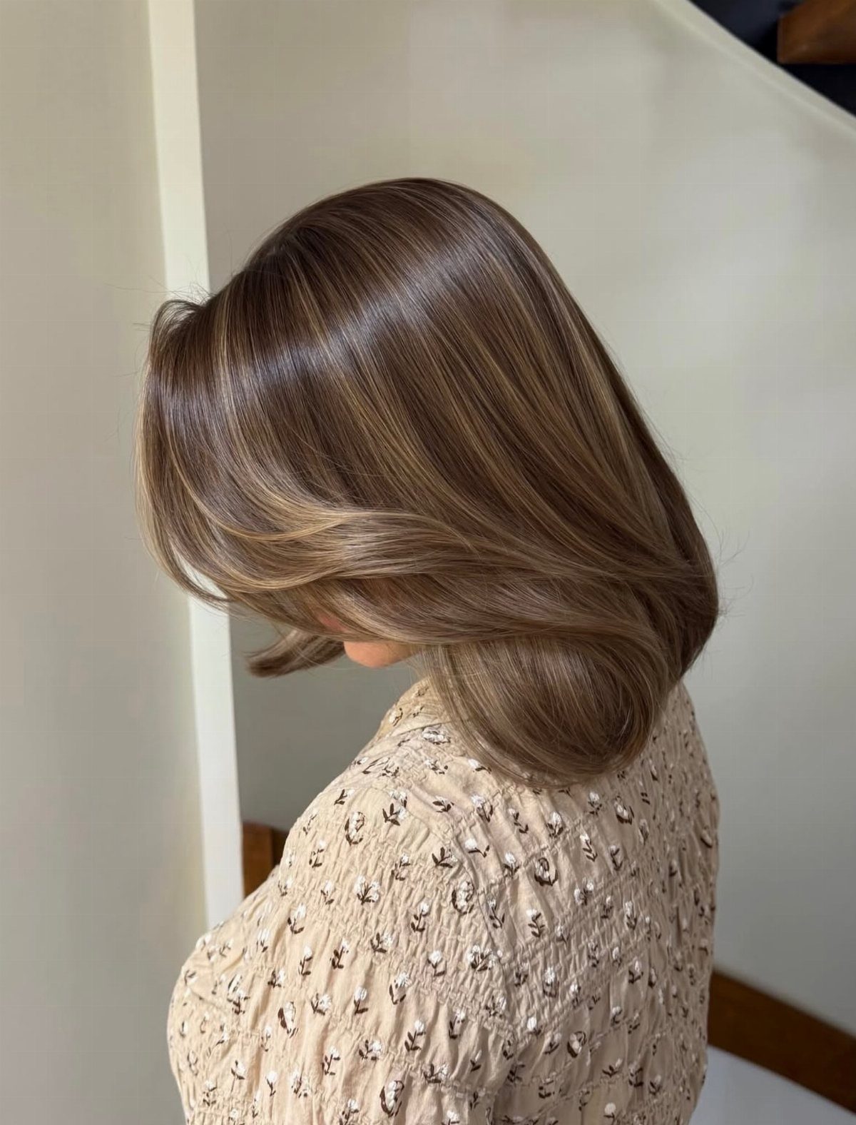 Brown layered bob with caramel highlights styled in soft, sweeping curves