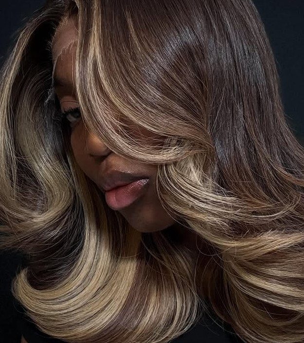 Woman's curled brown hair with broad golden blonde highlights framing her face
