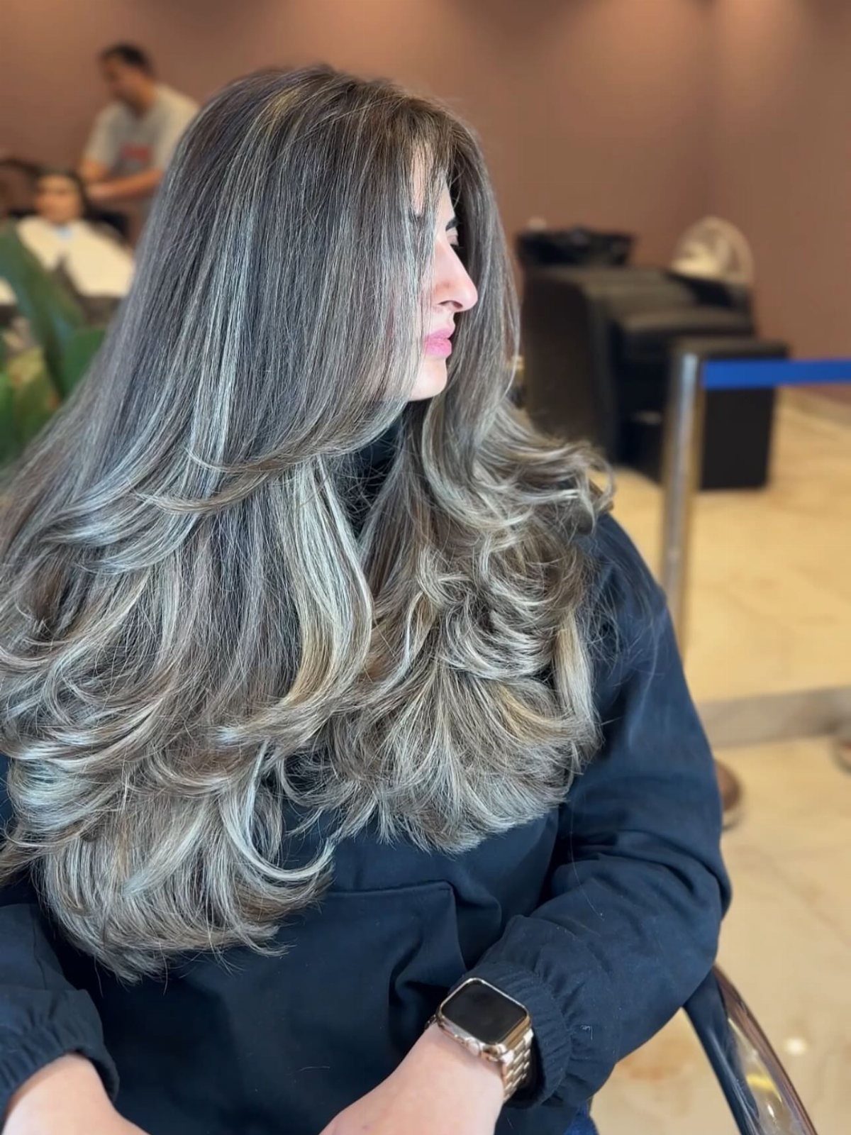 Long brown hair with silver-gray highlights styled in layered curls