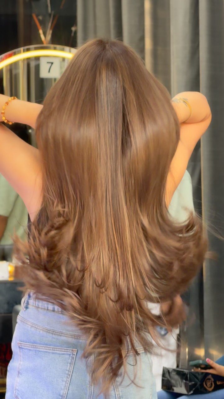 Long wavy brown hair with warm caramel and coppery highlights in a salon