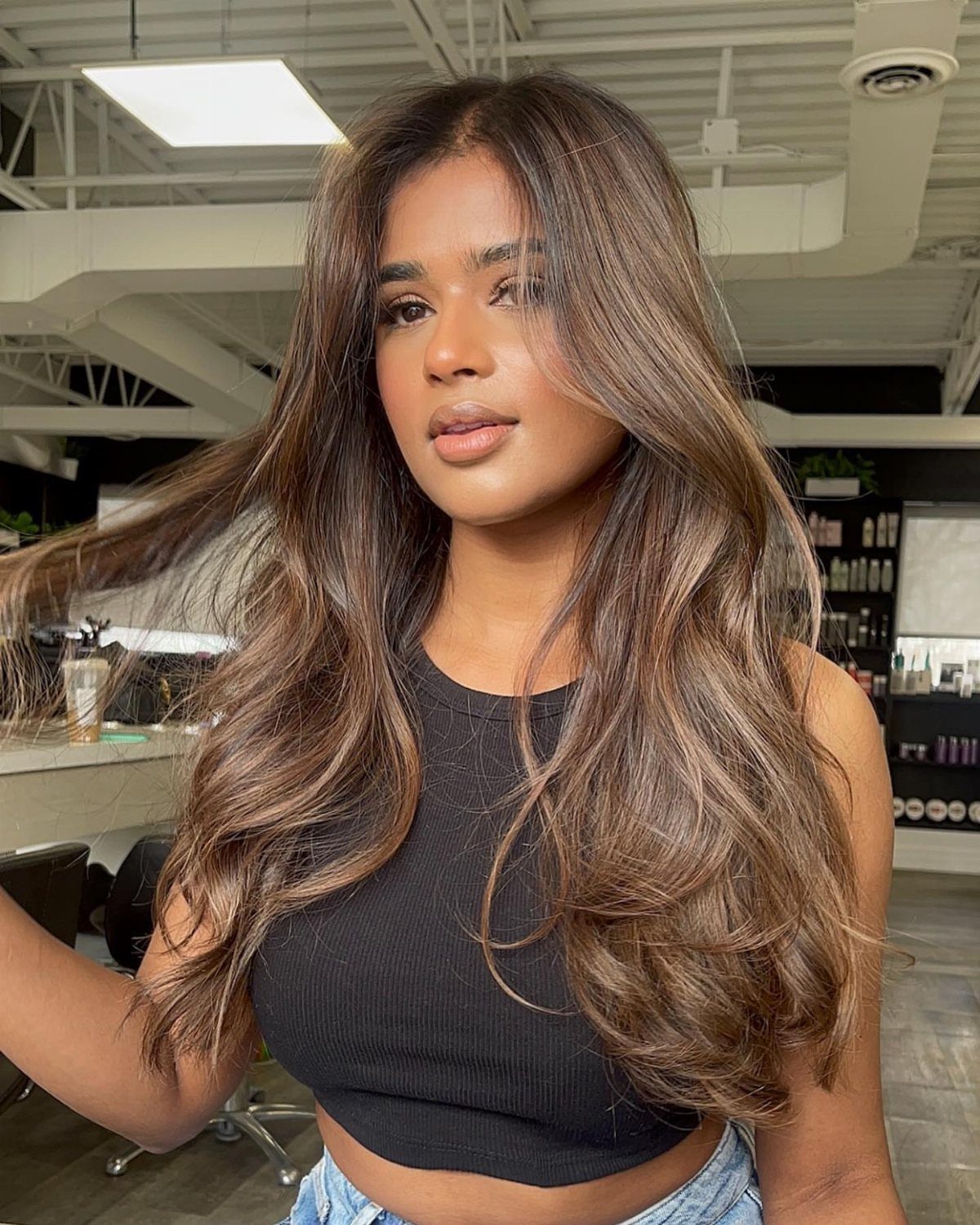 Woman showing long brown hair with caramel face-framing highlights and soft waves