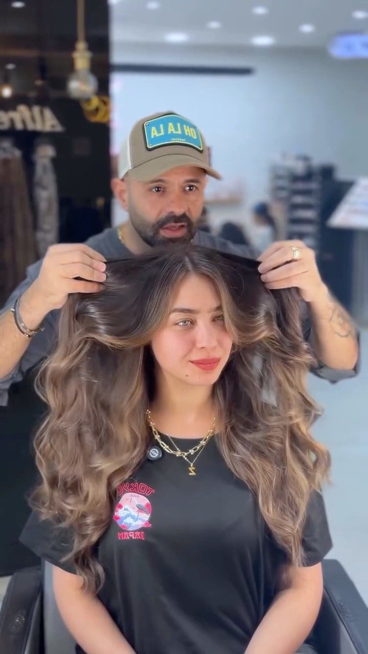 Long dark brown waves with broad caramel highlights shown in a salon