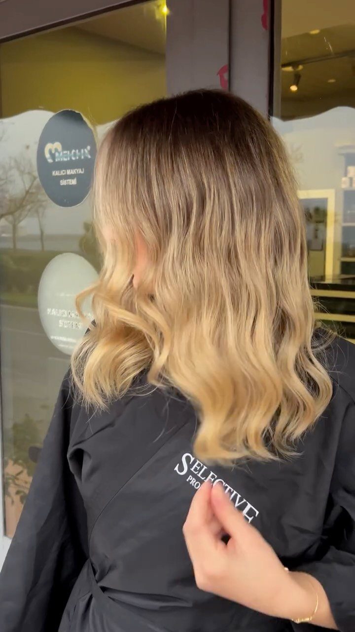Long wavy brown hair fades into caramel-blonde ends in a salon chair
