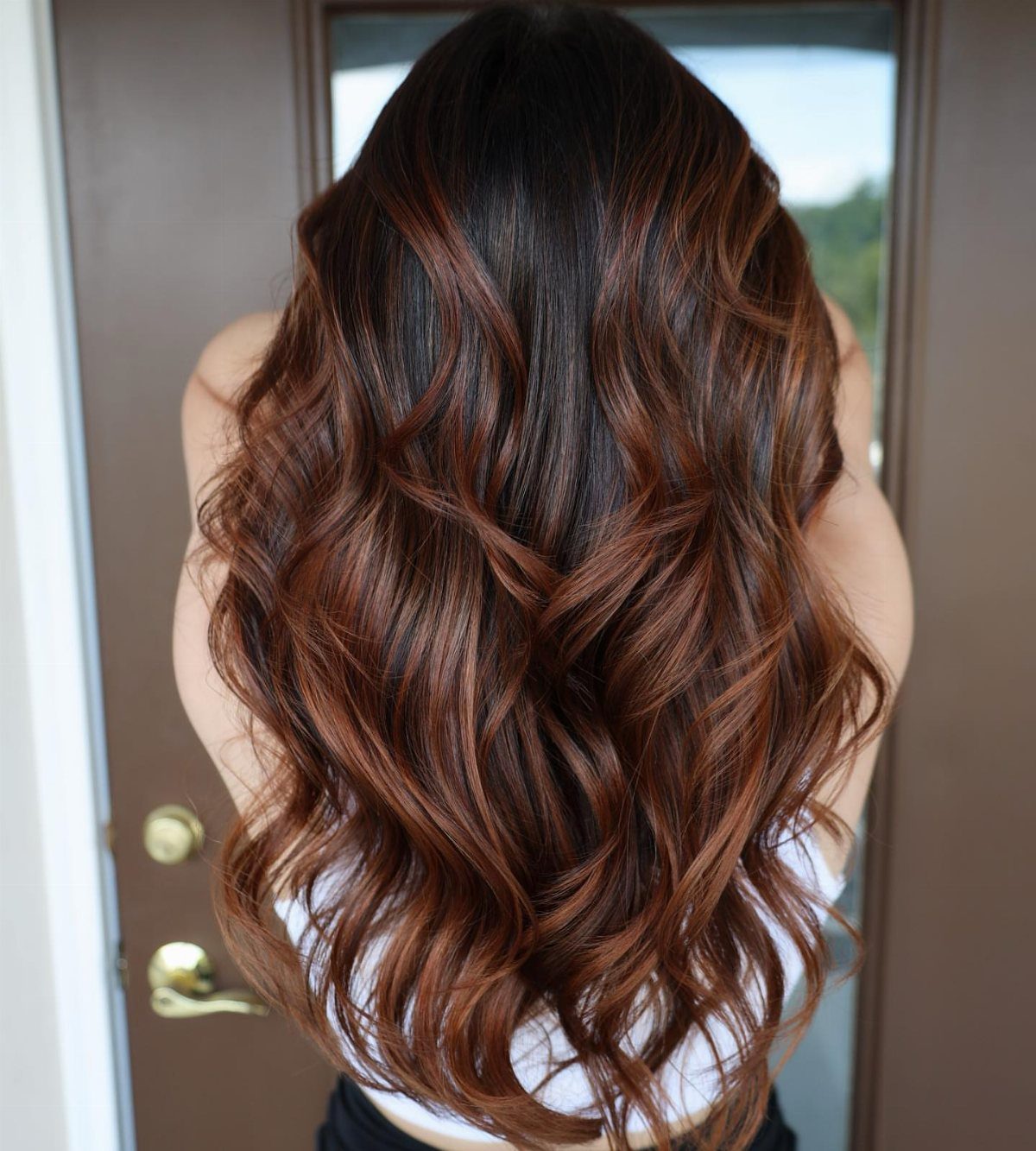 Long curled chocolate-brown hair with copper-caramel ends shown from behind