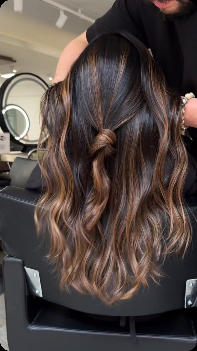 Long brown hair with muted caramel highlights styled in loose waves