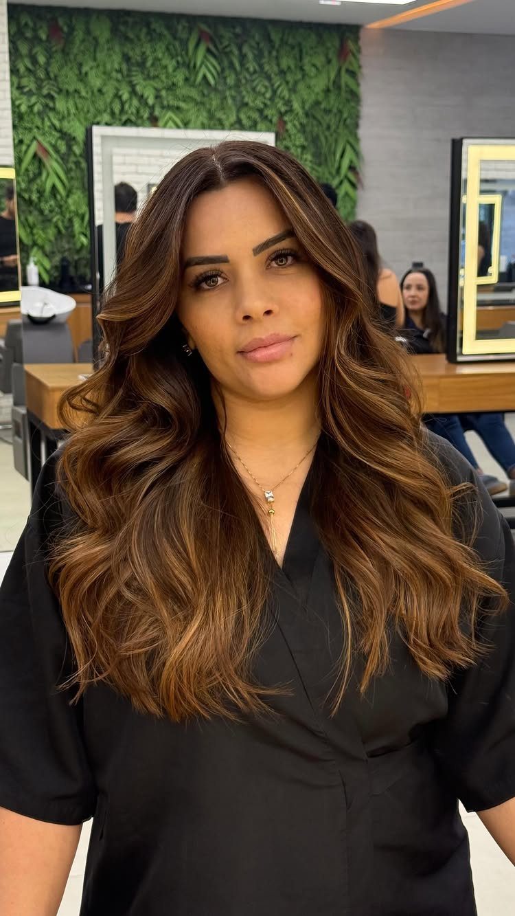 Woman with long chocolate-brown waves and reddish caramel-blonde highlights