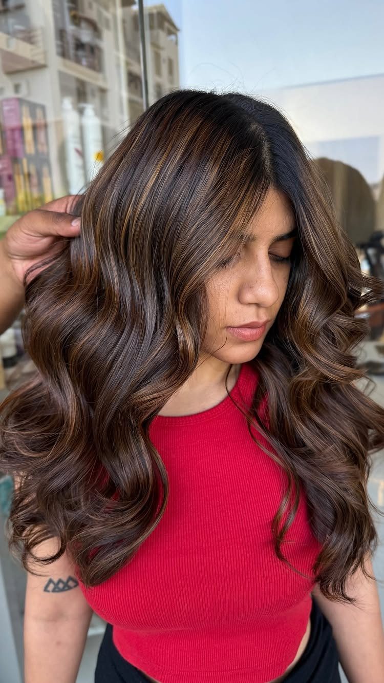 Woman with long wavy brown hair and sun-kissed caramel highlights outdoors