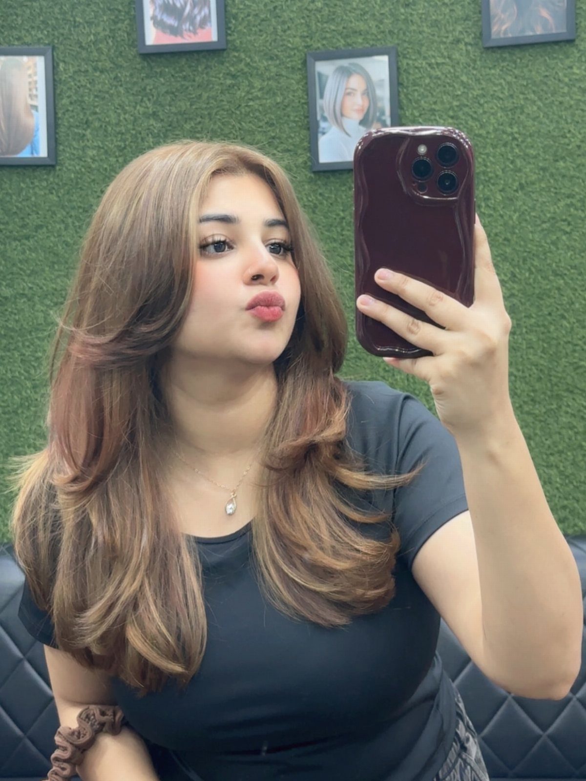 Long brown waves with lighter tawny highlights frame a mirror selfie