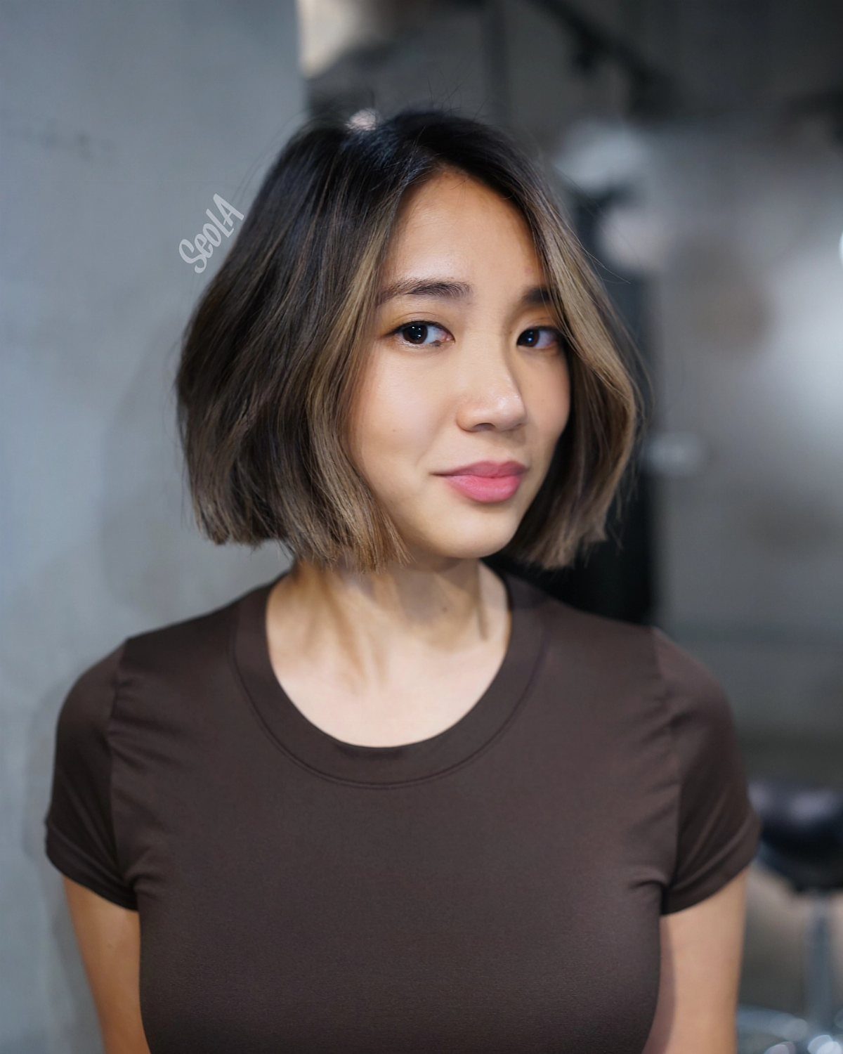 Woman with a short textured brunette bob and subtle lighter highlights